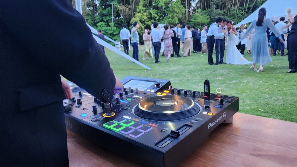 DJの手元と、その奥で芝生に集まるゲスト