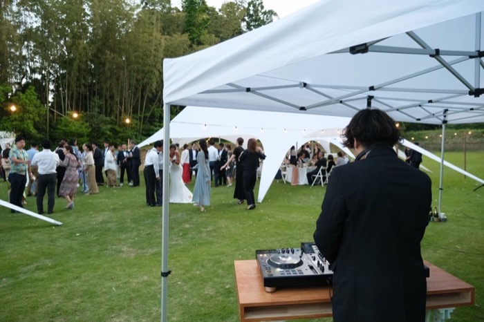 屋外のDJブースと、テント下に集まるゲスト