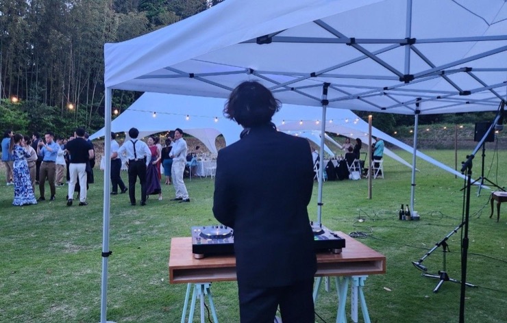 テント下のDJブースから芝生のゲストを見た、屋外ウェディングの様子