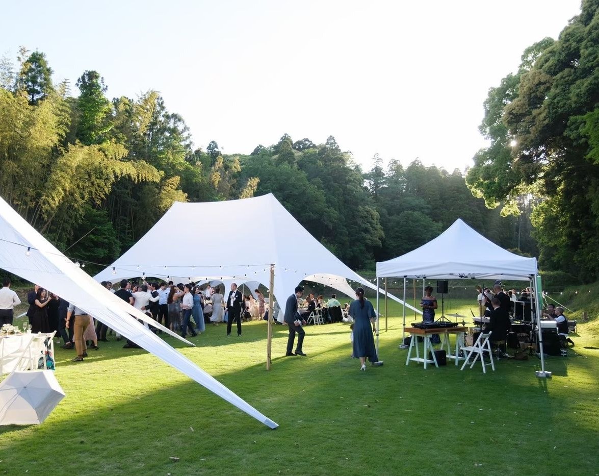 森に面した芝生に張られたテントと、屋外ウェディングの会場