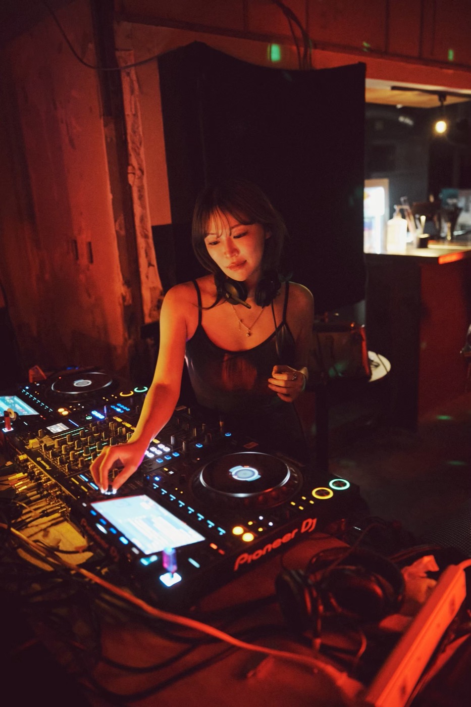 暗いクラブ。CDJ2台とミキサーに手を伸ばしている