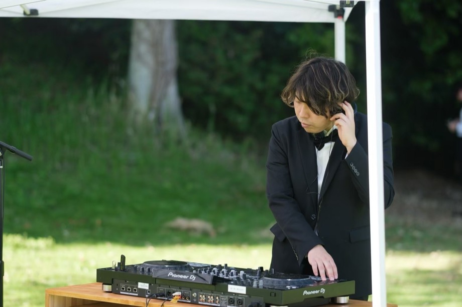 ヘッドホンで頭出しをする、タキシード姿のDJ